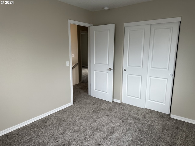 unfurnished bedroom featuring a closet and dark colored carpet