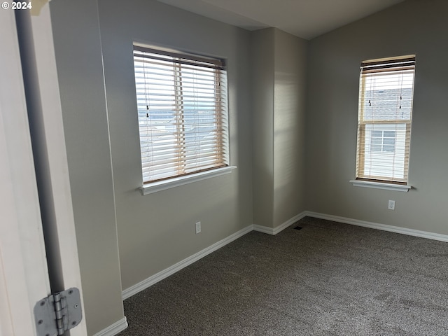 spare room with dark carpet