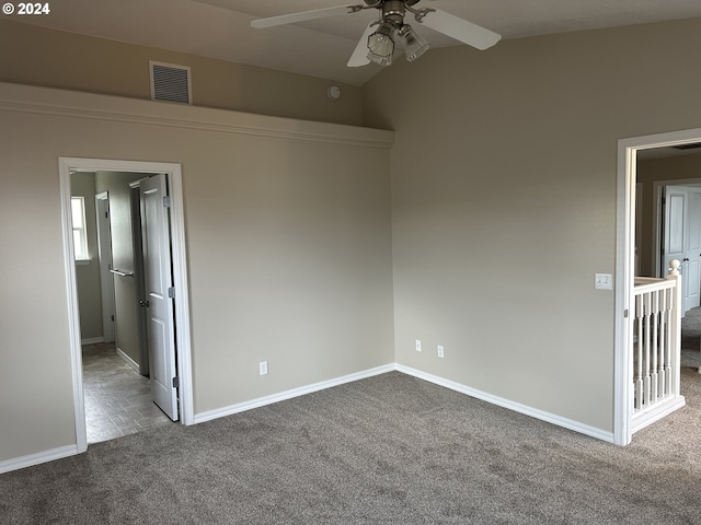 carpeted spare room featuring vaulted ceiling and ceiling fan