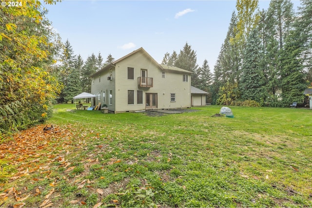 back of house with a balcony and a lawn