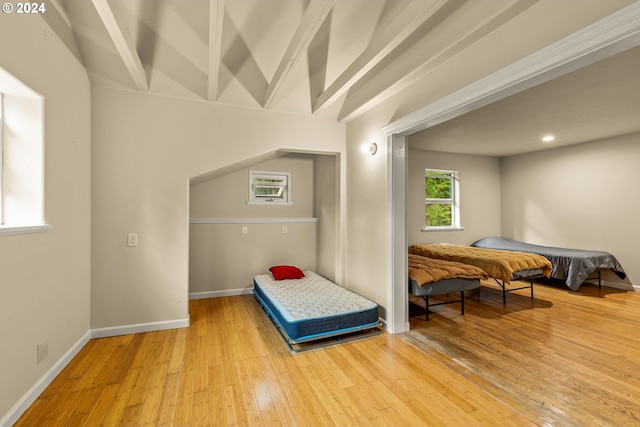 bedroom with lofted ceiling with beams and wood-type flooring