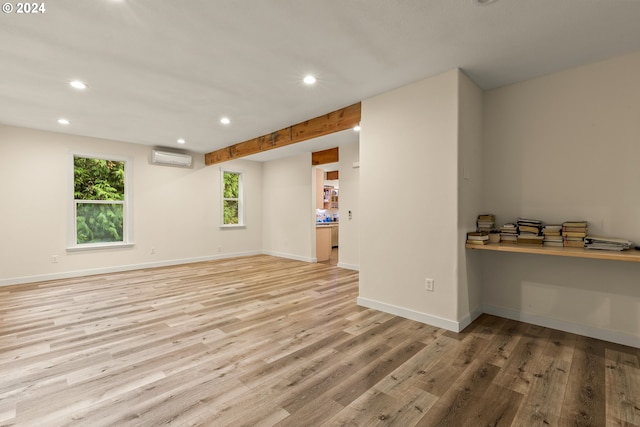 interior space with light hardwood / wood-style floors, a wall mounted AC, and built in desk