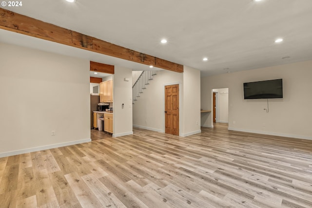 unfurnished living room featuring beamed ceiling and light hardwood / wood-style floors