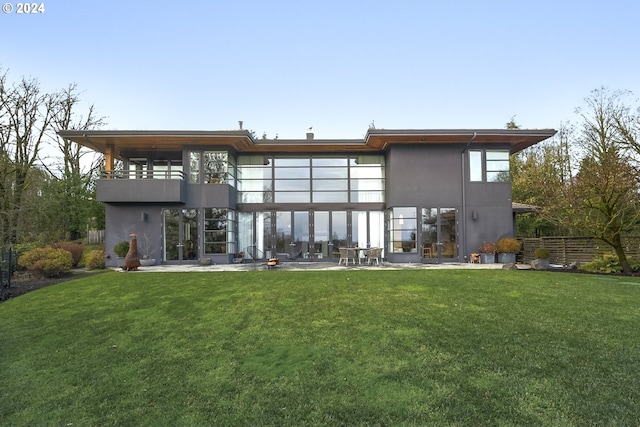 back of property featuring a lawn, a patio area, and a balcony