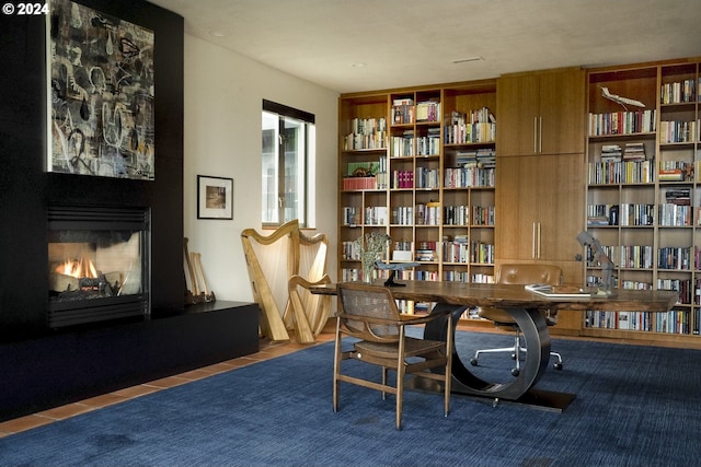 living area featuring a multi sided fireplace and dark tile patterned flooring