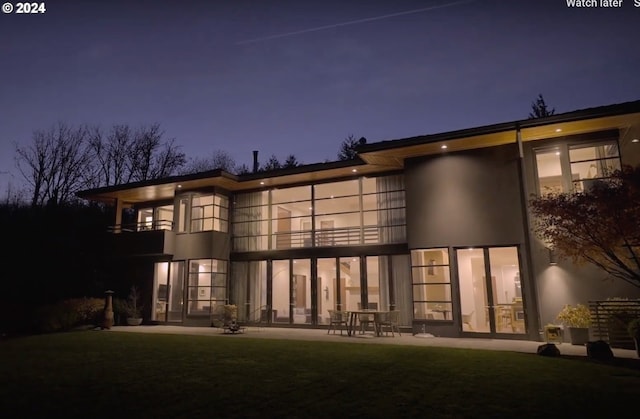 rear view of house featuring a patio, a balcony, and a lawn