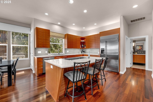 kitchen with a breakfast bar, visible vents, light countertops, appliances with stainless steel finishes, and an island with sink