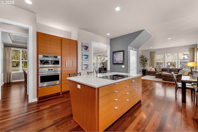 kitchen featuring a center island with sink, light countertops, double oven, open floor plan, and modern cabinets