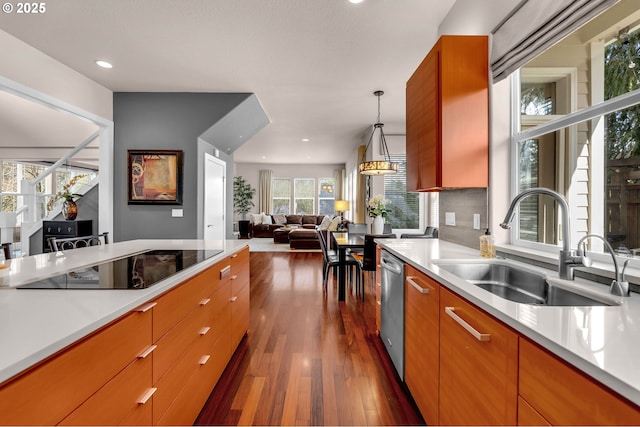 kitchen featuring open floor plan, light countertops, a sink, and black electric cooktop