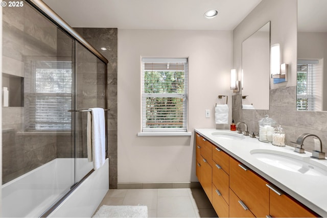 bathroom featuring double vanity, bath / shower combo with glass door, a sink, and tile patterned floors