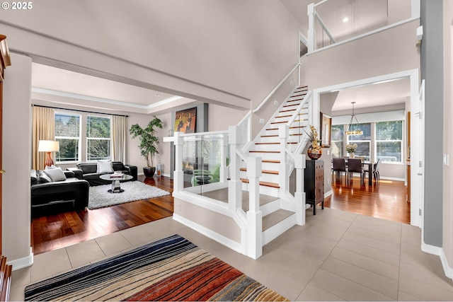 entryway with plenty of natural light, stairway, a notable chandelier, and light tile patterned flooring