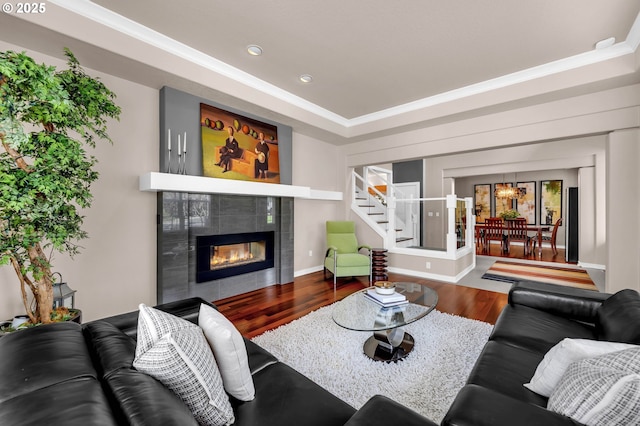 living room featuring recessed lighting, a tiled fireplace, wood finished floors, baseboards, and stairs