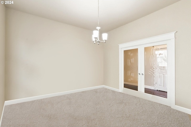 unfurnished room with carpet floors, a notable chandelier, and french doors