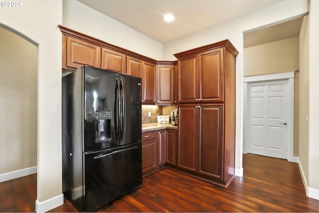 kitchen with black fridge, dark wood-type flooring, and backsplash