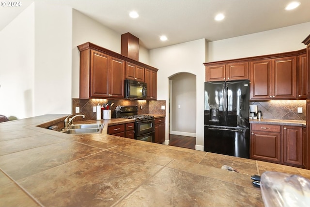 kitchen with tasteful backsplash, sink, tile countertops, and black appliances