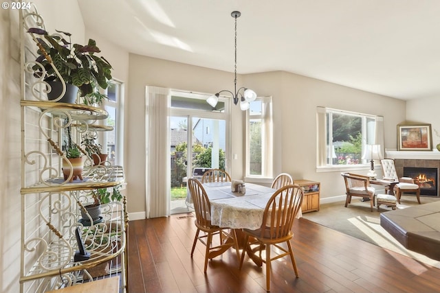 dining room featuring dark wood-type flooring, a fireplace, and a healthy amount of sunlight