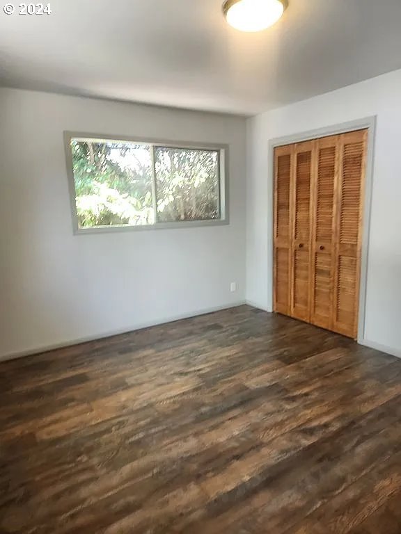 unfurnished bedroom with dark wood-type flooring and a closet