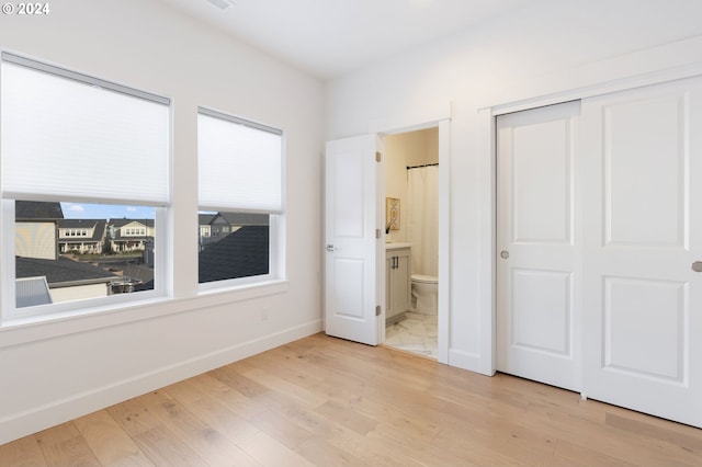 unfurnished bedroom featuring light hardwood / wood-style floors, a closet, and ensuite bathroom