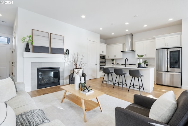 living room with sink, a fireplace, and light wood-type flooring