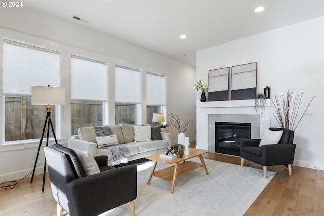 living room with light wood-type flooring and a tiled fireplace