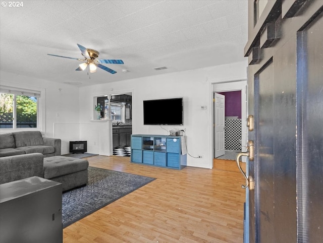 living room with a textured ceiling, hardwood / wood-style flooring, and ceiling fan