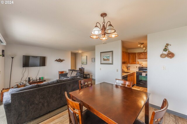 dining room with sink, light hardwood / wood-style flooring, and a notable chandelier