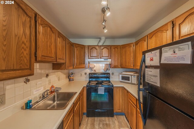 kitchen with sink, backsplash, black appliances, and light hardwood / wood-style flooring