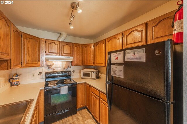 kitchen featuring sink, black appliances, decorative backsplash, and light hardwood / wood-style floors