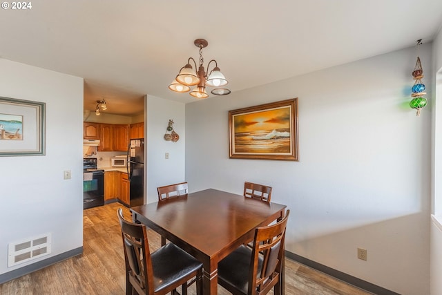 dining room with light hardwood / wood-style flooring and a notable chandelier