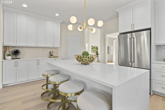 kitchen with light hardwood / wood-style flooring, tasteful backsplash, decorative light fixtures, and an inviting chandelier