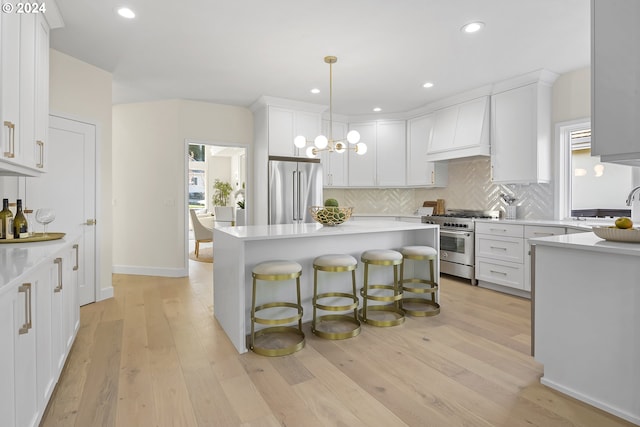 kitchen with pendant lighting, white cabinets, high end appliances, premium range hood, and a kitchen bar