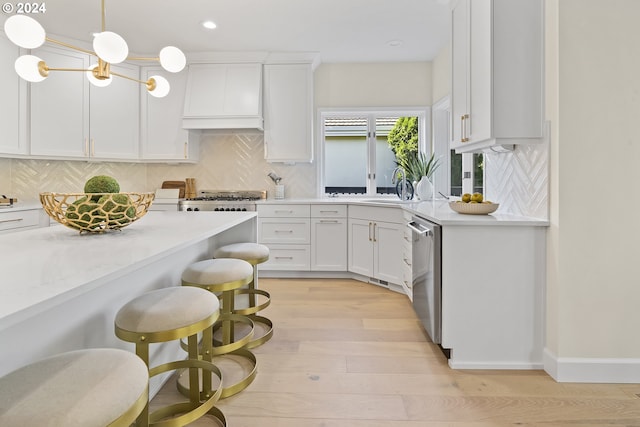 kitchen featuring backsplash, a kitchen bar, light wood-type flooring, premium range hood, and stainless steel dishwasher