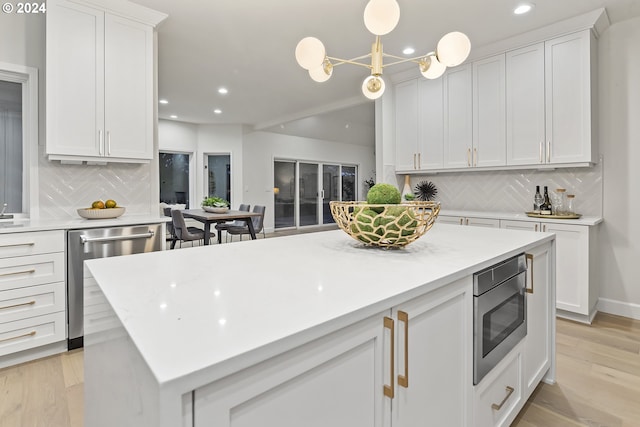 kitchen with backsplash, white cabinetry, hanging light fixtures, and stainless steel appliances