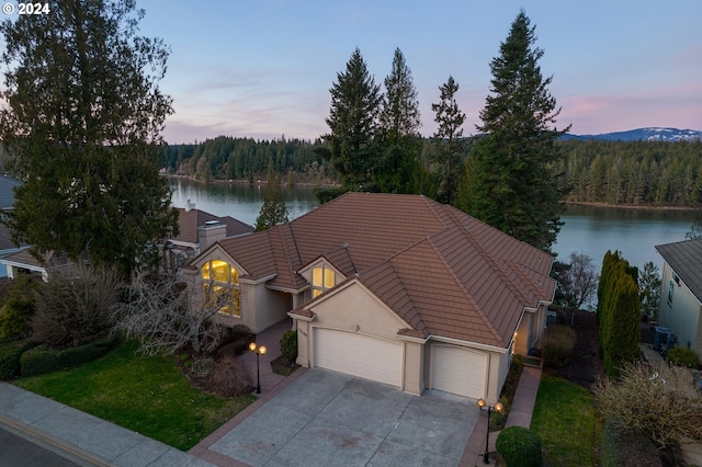 view of front of home with central air condition unit, a water view, and a garage