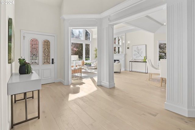 foyer entrance with a high ceiling, light hardwood / wood-style floors, and ornate columns