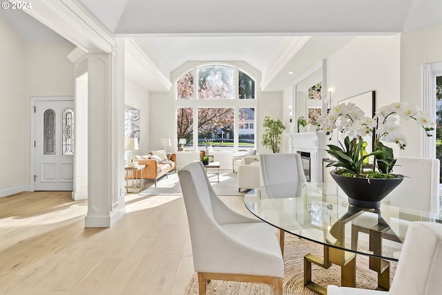 dining space with a towering ceiling, ornamental molding, and light wood-type flooring