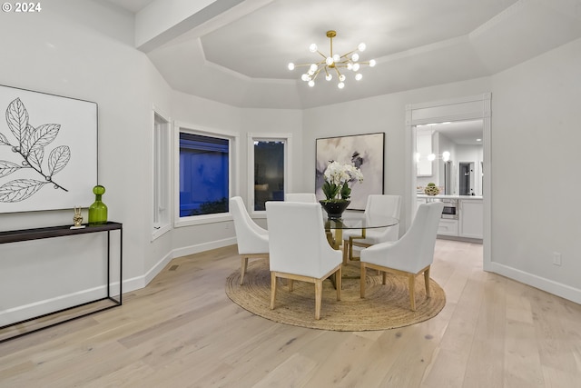 dining room featuring a chandelier, a raised ceiling, and light hardwood / wood-style floors