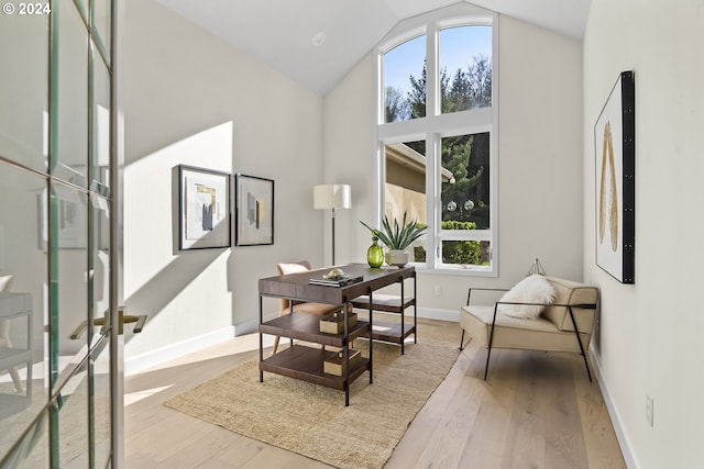 sitting room with high vaulted ceiling and light wood-type flooring