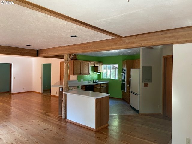 725 Snowden Rd, White Salmon, WA 98672 - kitchen with freestanding refrigerator, dishwasher, a sink, hardwood / wood-style floors, and beamed ceiling