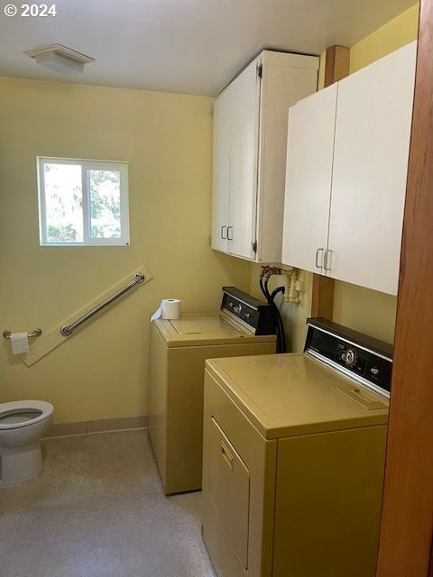 clothes washing area featuring washing machine and clothes dryer and cabinets