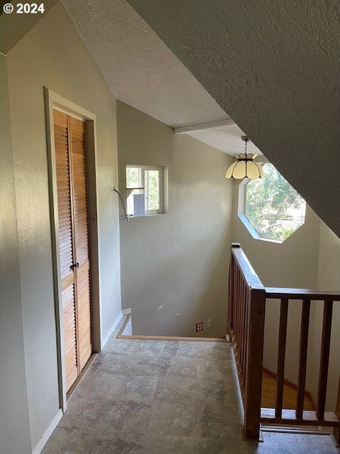 725 Snowden Rd, White Salmon, WA 98672 - hallway featuring a textured ceiling, baseboards, vaulted ceiling, and an upstairs landing