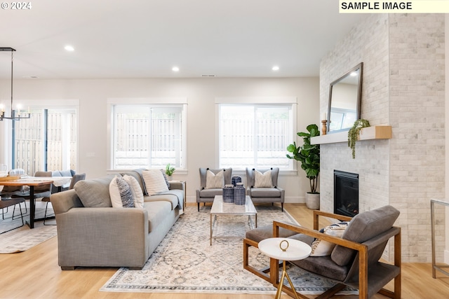 living room featuring a notable chandelier, a wealth of natural light, a fireplace, and light hardwood / wood-style floors