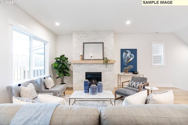 living room with lofted ceiling, a fireplace, and light hardwood / wood-style floors