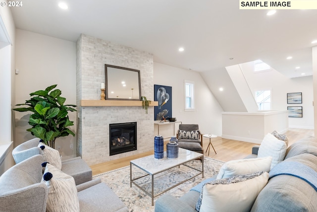 living room with lofted ceiling, a fireplace, and light hardwood / wood-style floors