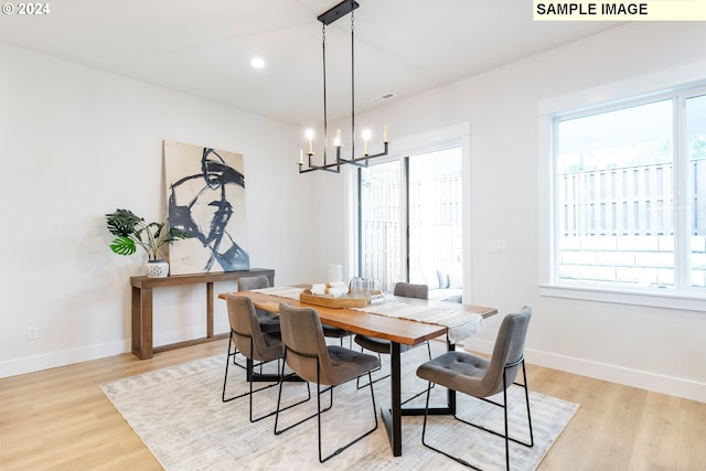 dining room with a healthy amount of sunlight, a chandelier, and light wood-type flooring