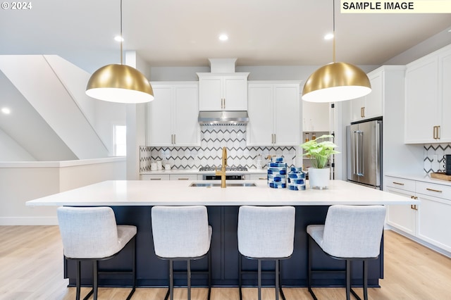 kitchen with white cabinetry, high end fridge, pendant lighting, and a kitchen island with sink