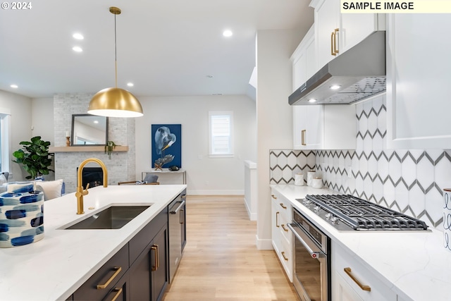 kitchen with pendant lighting, sink, stainless steel appliances, tasteful backsplash, and extractor fan