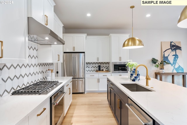 kitchen featuring sink, backsplash, stainless steel appliances, ventilation hood, and decorative light fixtures