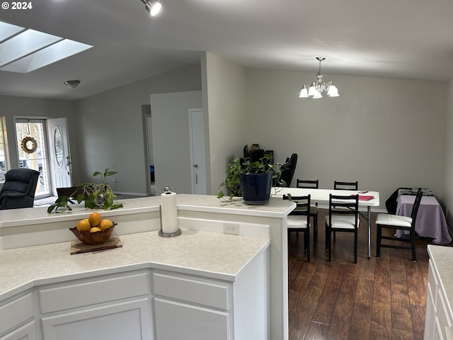 kitchen featuring lofted ceiling with skylight, a notable chandelier, dark hardwood / wood-style floors, white cabinetry, and hanging light fixtures