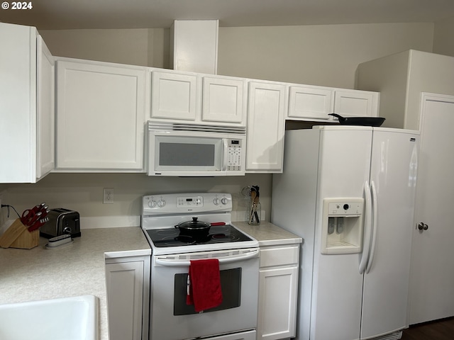 kitchen with white cabinets, dark wood-type flooring, and white appliances